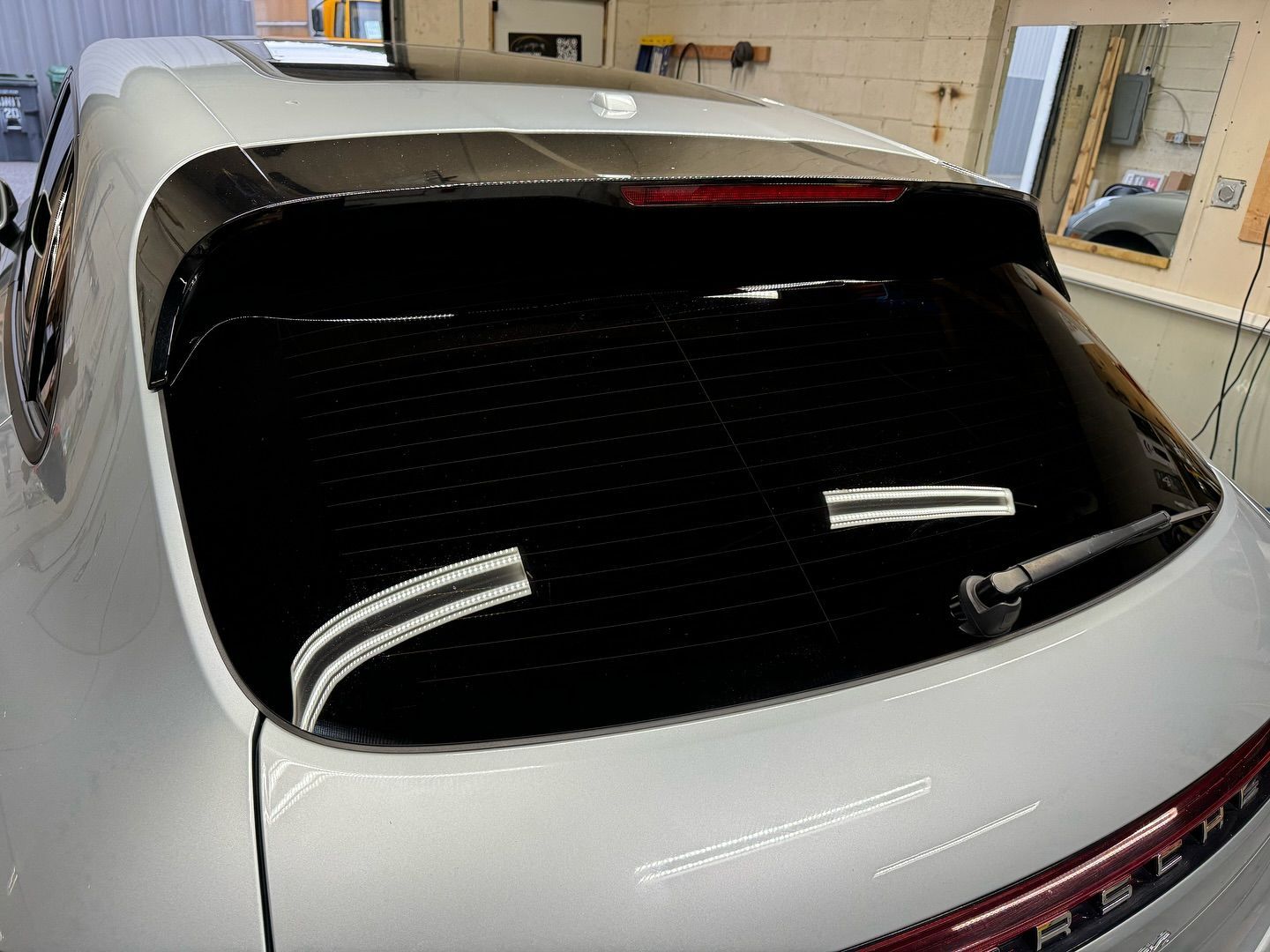 A silver porsche is parked in a garage.