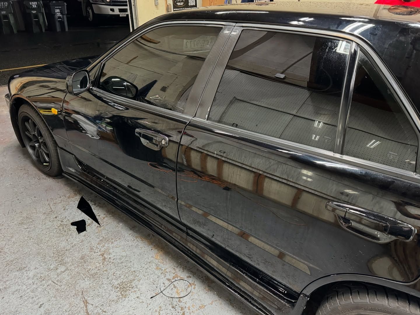 A black car with tinted windows is parked in a garage.