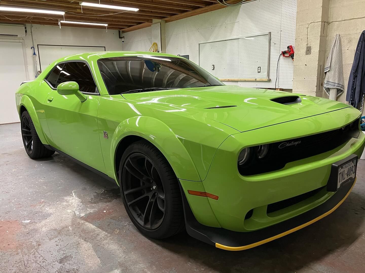A green dodge challenger is parked in a garage.