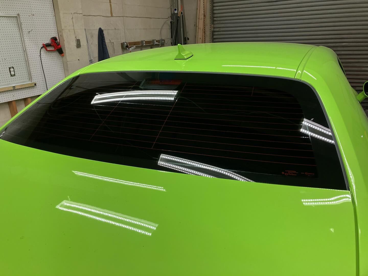 A green car with a black windshield is parked in a garage.