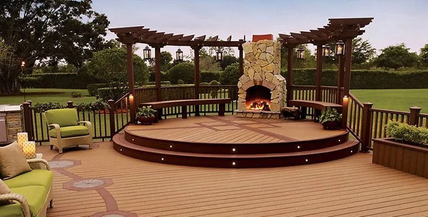 Outdoor patio with stone fireplace, pergola, seating, and brick flooring.