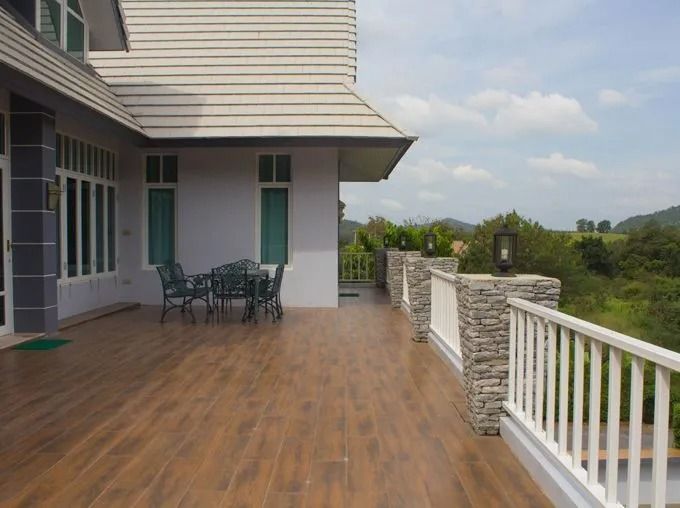 A house with a patio overlooking a scenic landscape. The patio has a table, chairs, and a white railing.