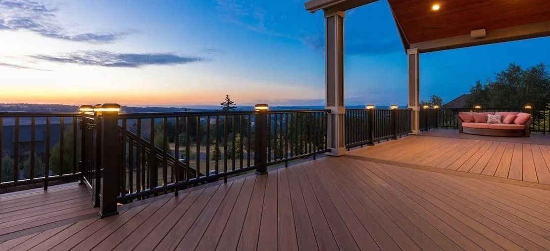 Wooden deck with a view of the sunset, a railing with lights, and a seating area.
