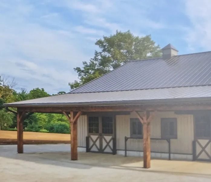 Barn with wood frame porch, gray metal roof, and white siding; sunny day.