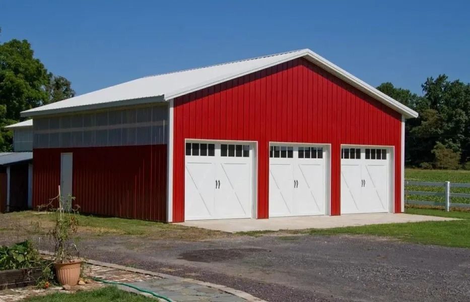 Red and white garage with three doors on a concrete pad, set on a sunny day.