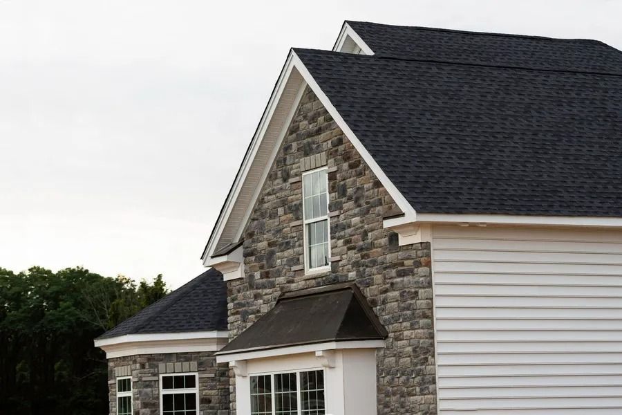 Stone and white siding house with dark roof.