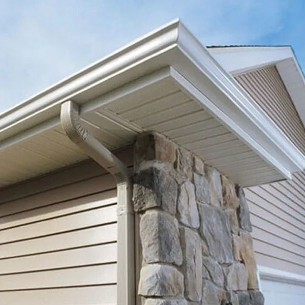 Beige gutters and downspout on a house with stone and siding accents.