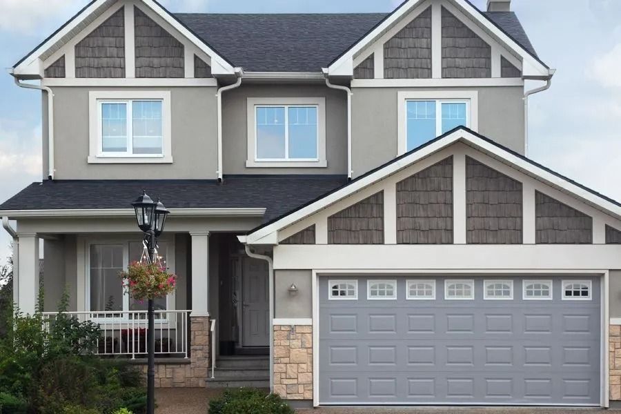 Two-story house with gray exterior, dark roof, light brown trim, and gray garage door.