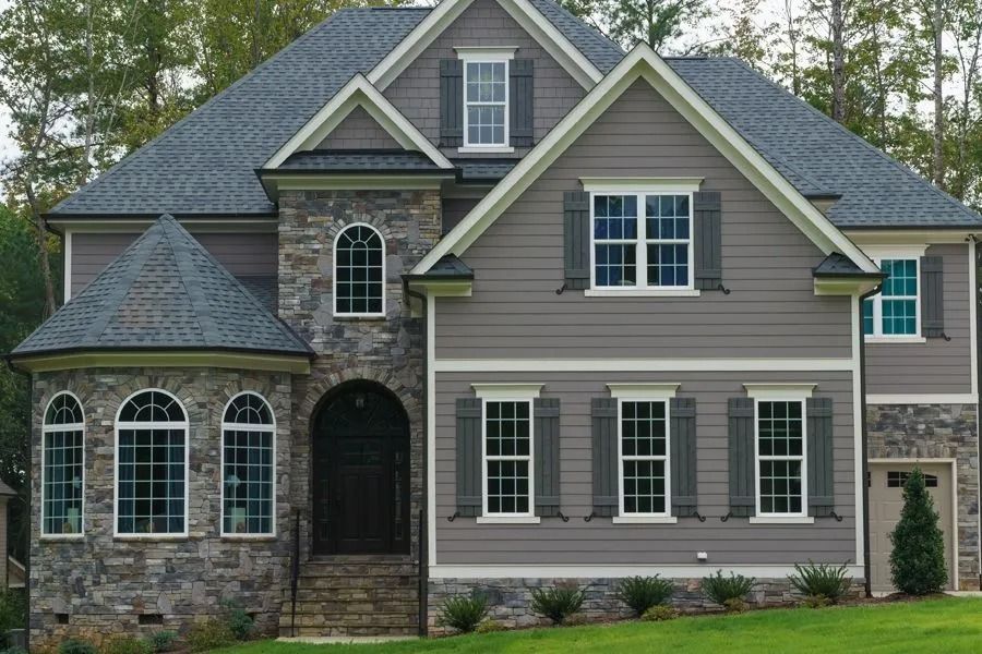Two-story gray house with stone accents, arched windows, and blue shutters.