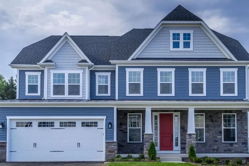 Two-story blue house with a white garage door and a red front door.