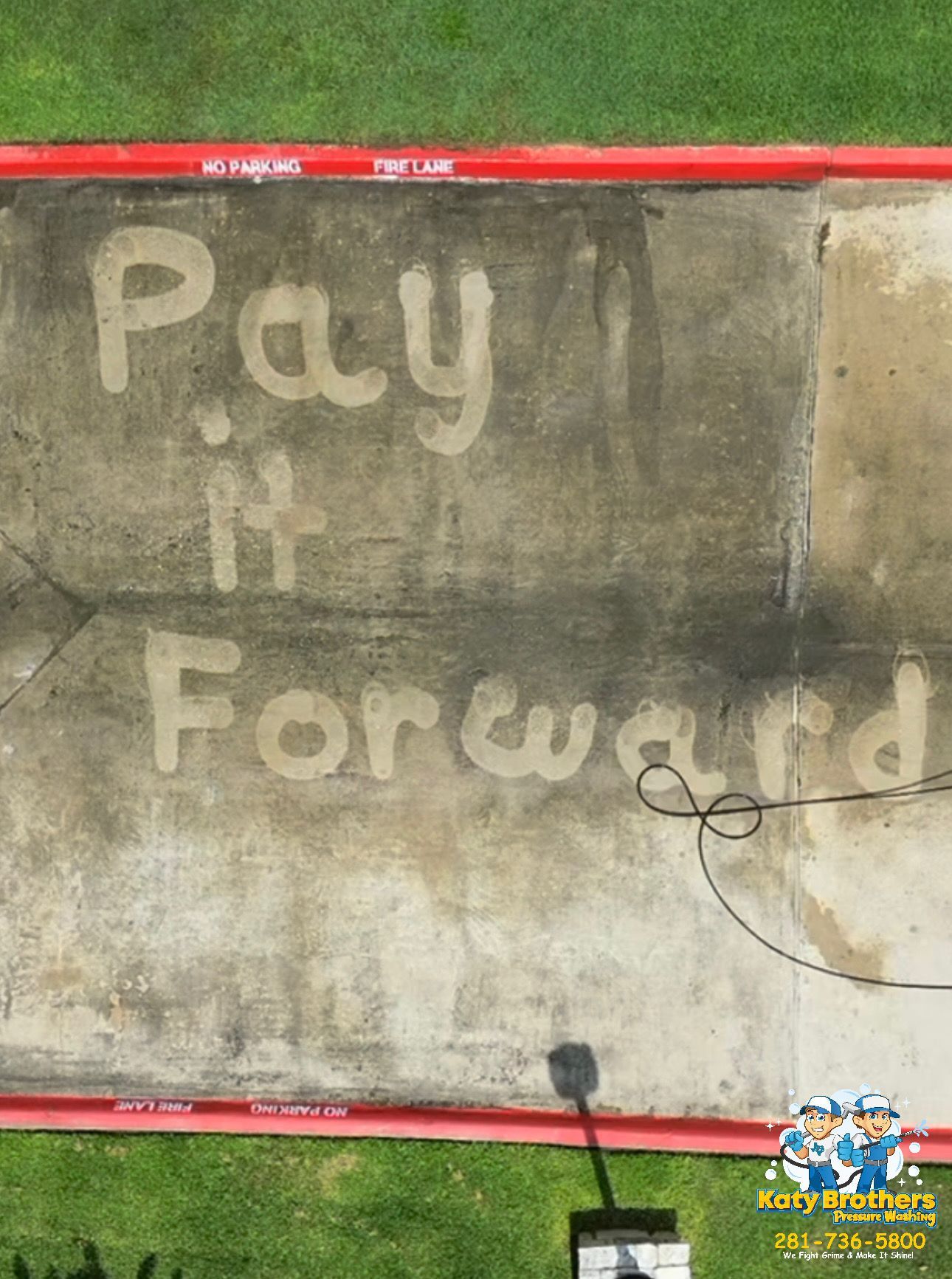 Chalk message on pavement reads Pay it Forward, bordered in red beside grass.