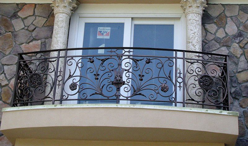 A balcony with a wrought iron railing and a sliding glass door