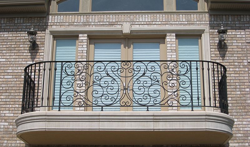 A balcony with a wrought iron railing on a brick building