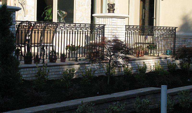 A fence with a greek key design is in front of a house