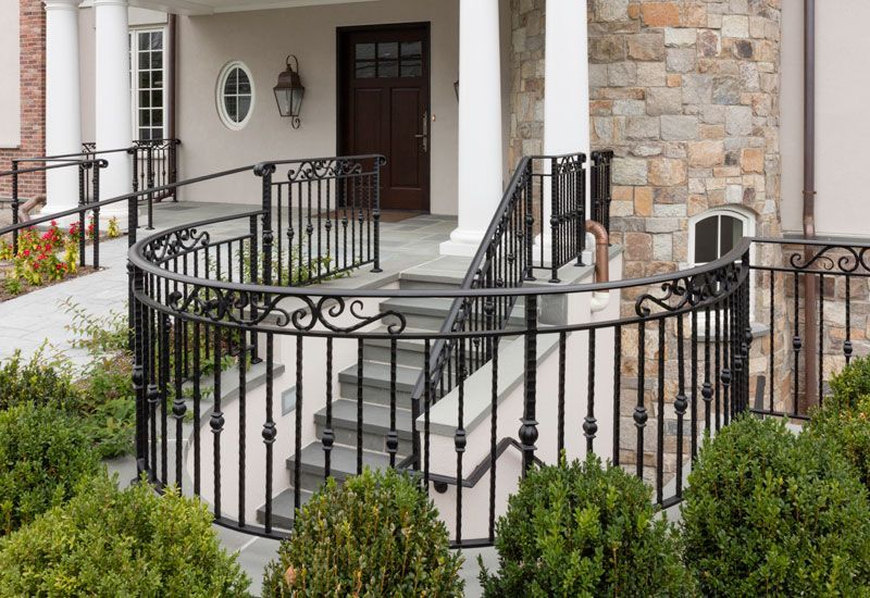 A wrought iron railing surrounds a set of stairs leading up to a porch.