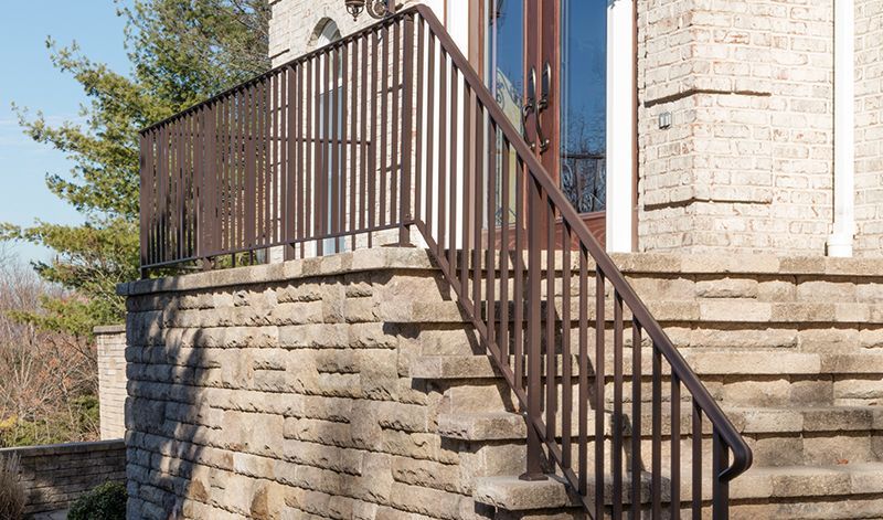 A set of stairs leading up to a brick building with a railing.