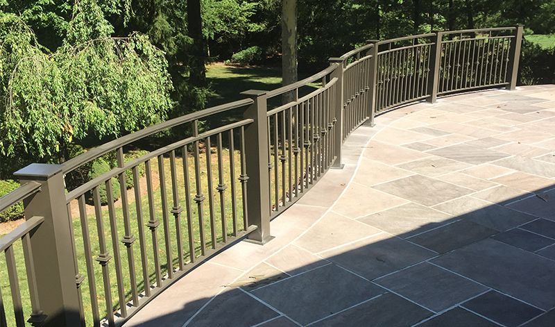A wrought iron railing surrounds a patio with trees in the background.