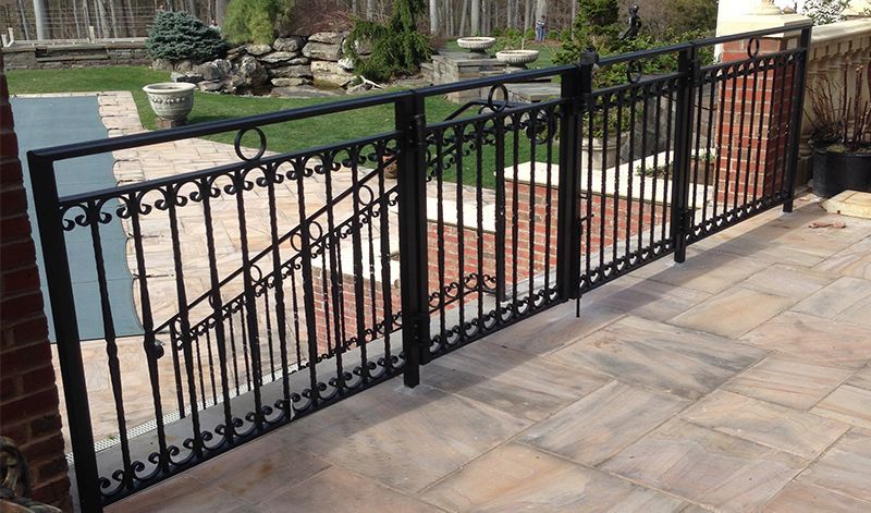 A wrought iron fence is sitting on a tiled patio next to a pool.