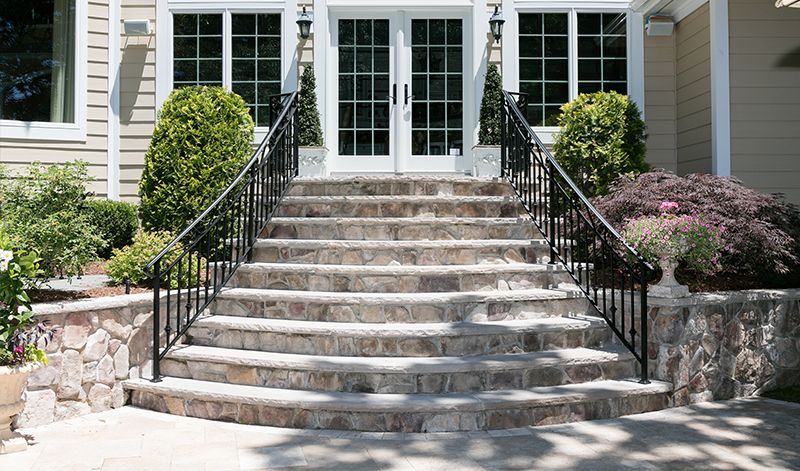 A set of stairs leading up to a house with a wrought iron railing.