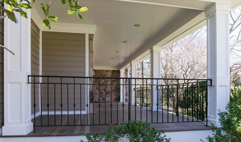 The porch of a house with a wrought iron railing.