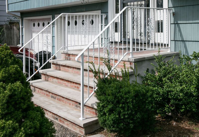 A house with stairs and a white railing in front of it.