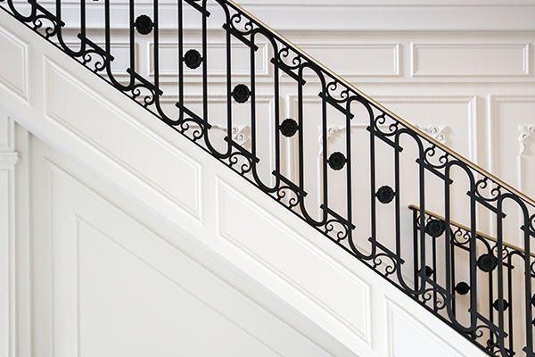 A staircase with a wrought iron railing and white walls