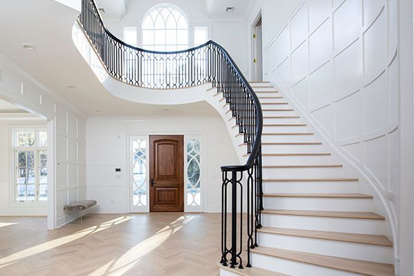 An empty house with a curved staircase and a wooden door.
