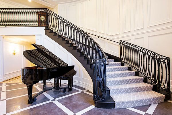 A grand piano is sitting next to a curved staircase.