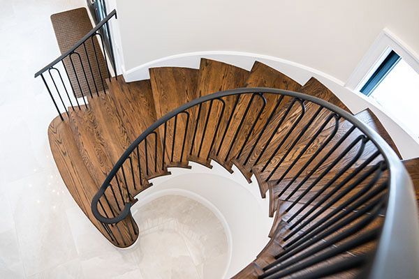 A spiral staircase with wooden steps and a metal railing in a house.