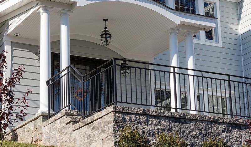 A large white house with a porch and a black railing.