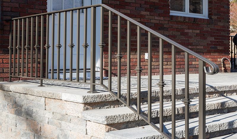 A wrought iron railing on a set of stairs in front of a brick building.