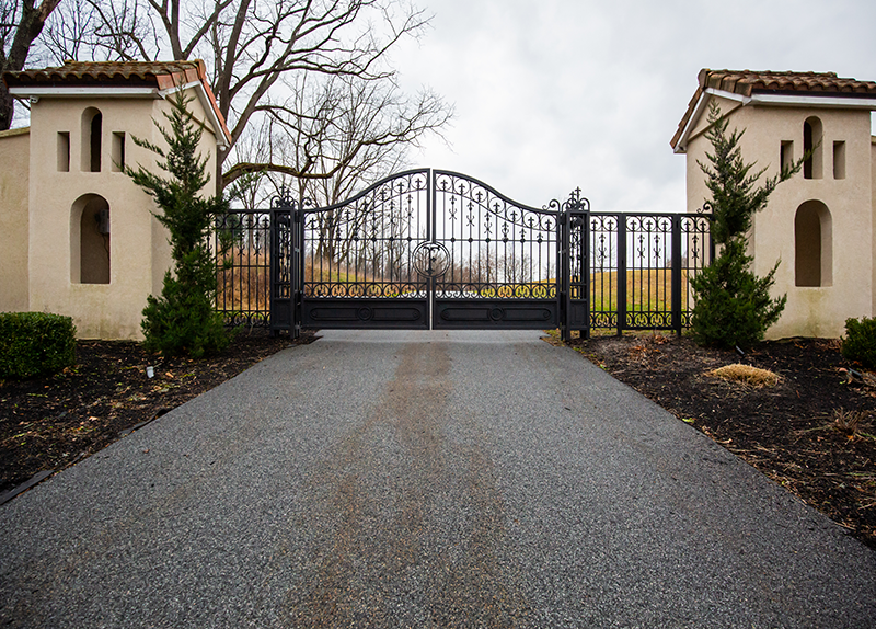 A gated driveway with a wrought iron gate in the middle