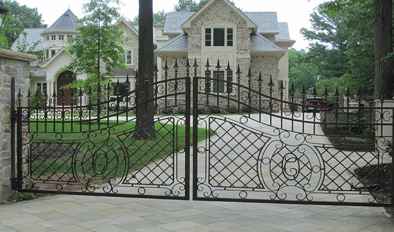 A large house is behind a wrought iron gate