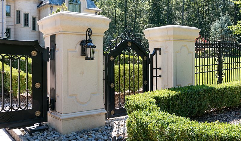 A large house with a gate and pillars in front of it.