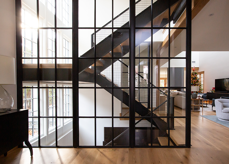 A staircase is visible through a glass wall in a living room.