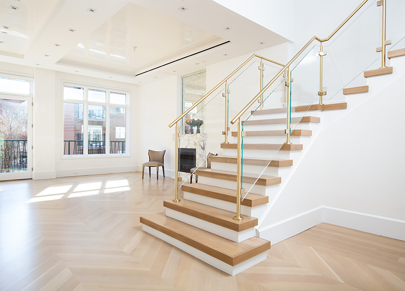 A modern staircase with wooden steps and a glass railing in a living room.