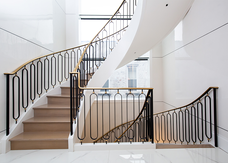 A curved staircase with a black railing and wooden steps