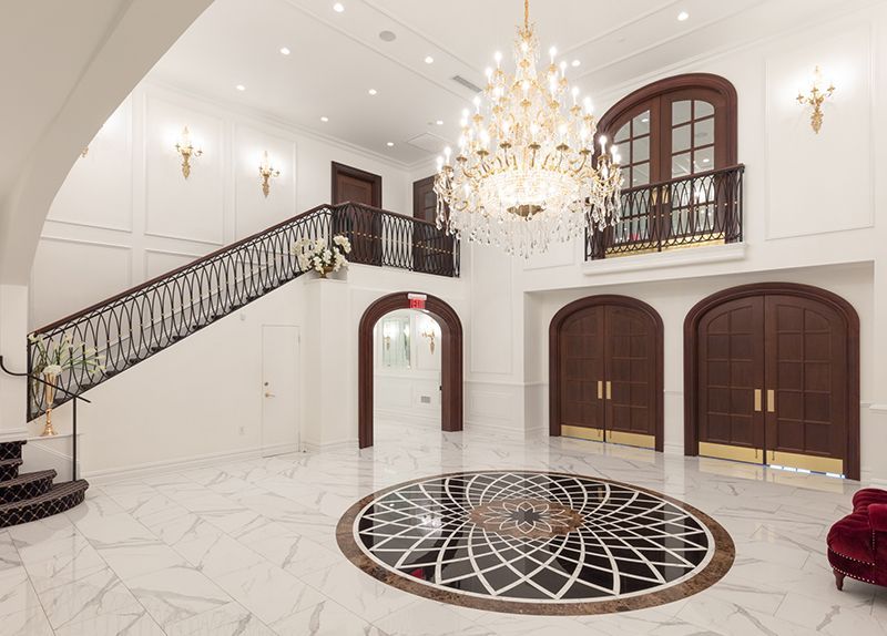 A large curved staircase in a hallway with a chandelier hanging from the ceiling.