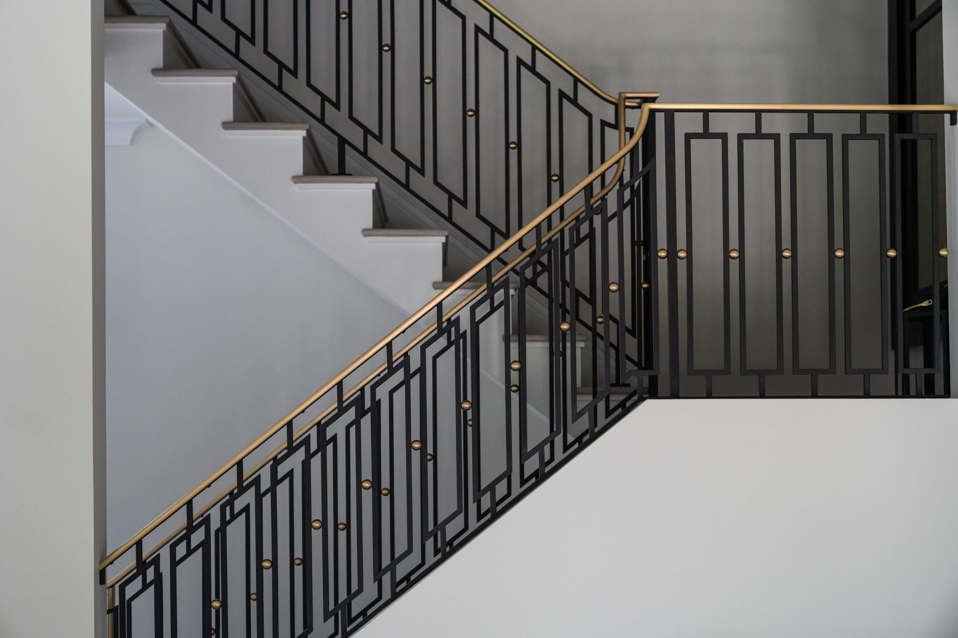 A close up of a staircase with a wrought iron railing in a building.