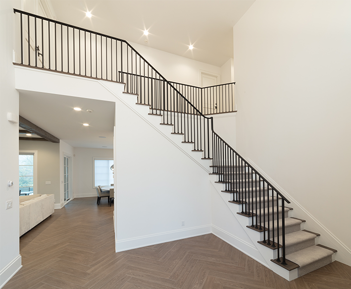 A staircase with a black railing is leading up to the second floor of a house.