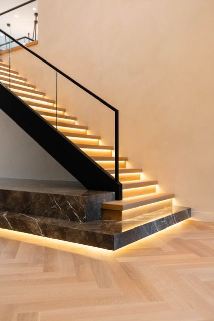A staircase with lights on the steps and a glass railing