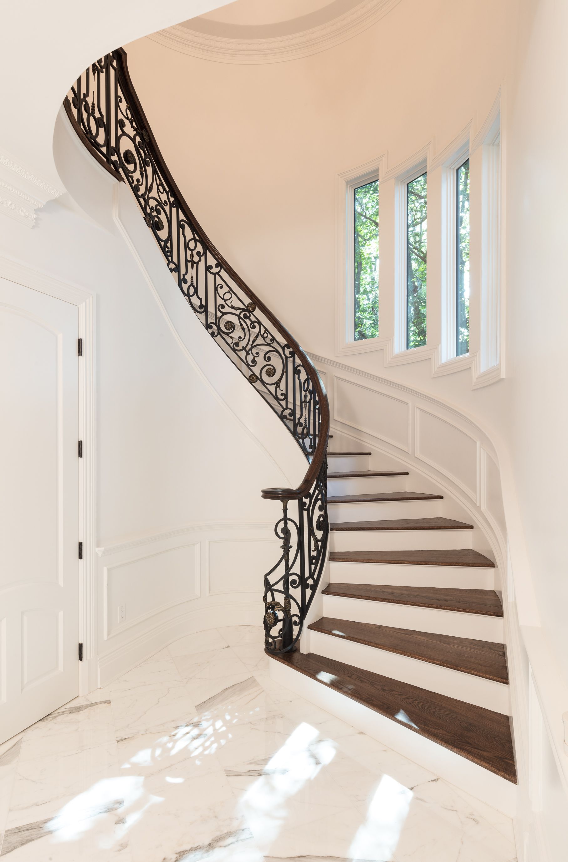 A curved staircase with a wrought iron railing in a house