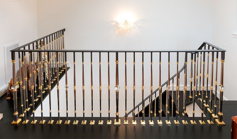 A staircase with a wrought iron railing and a light on the wall.