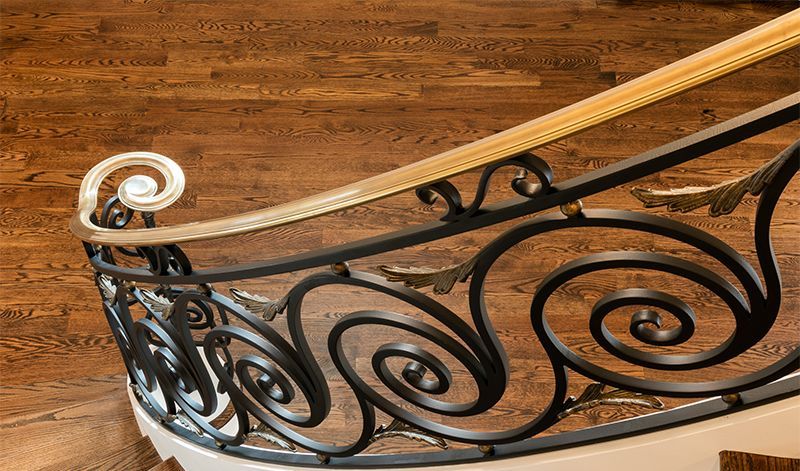 A close up of a wrought iron railing on a wooden staircase.