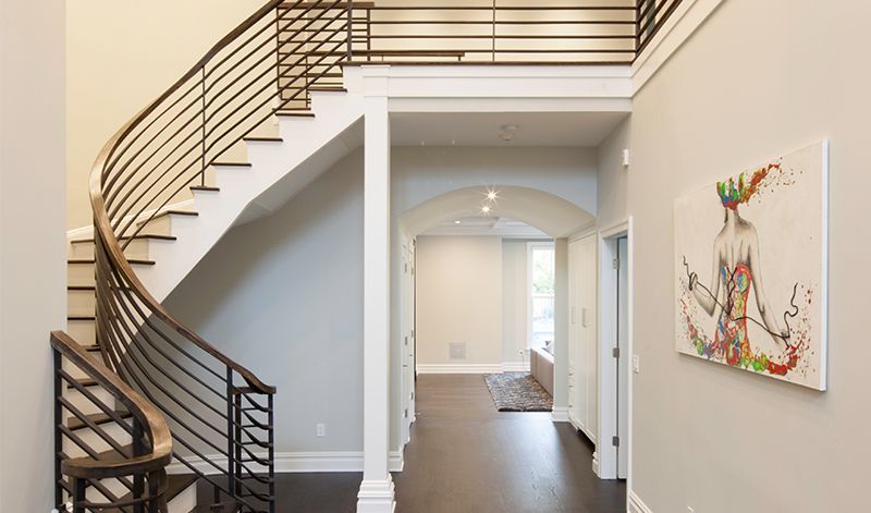 A large lobby with a chandelier hanging from the ceiling and a staircase.