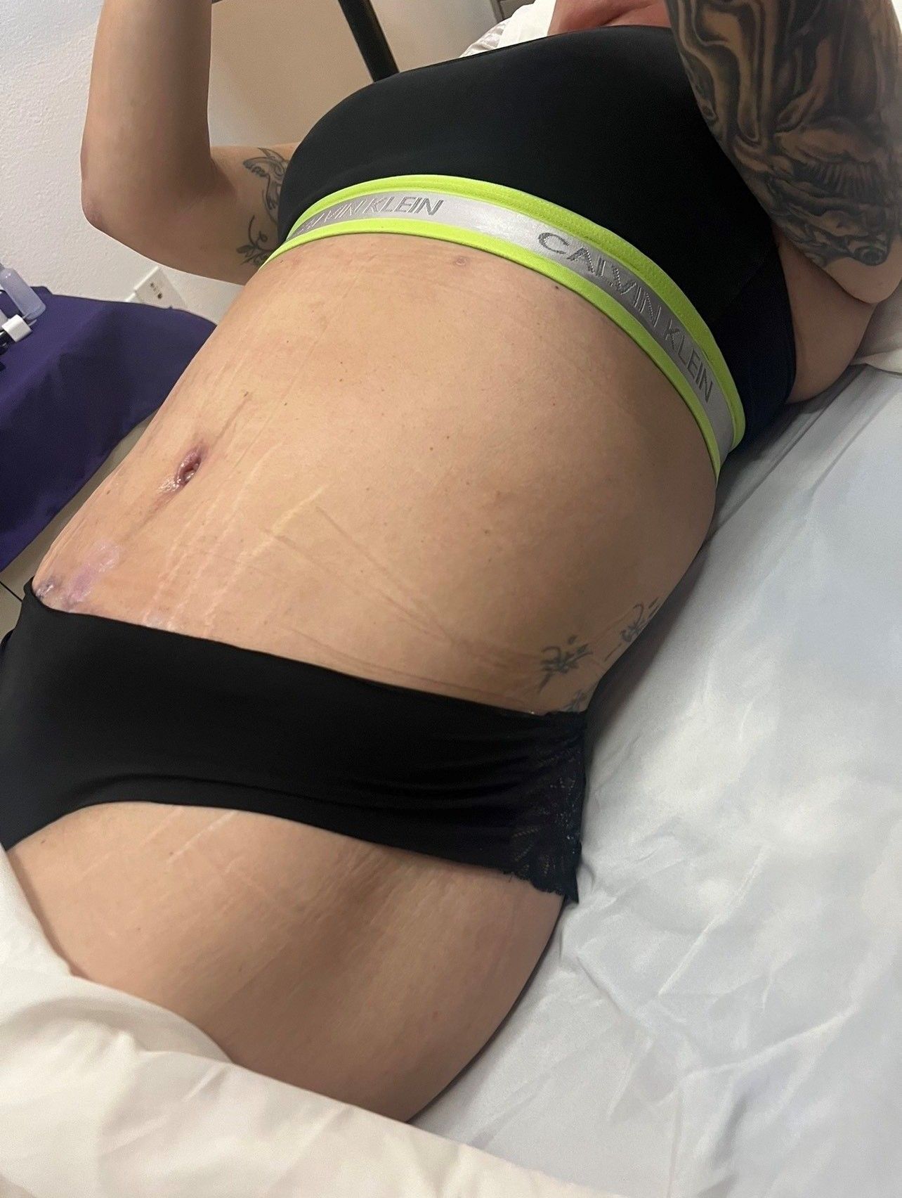 A woman is laying on a bed with a tattoo on her arm.