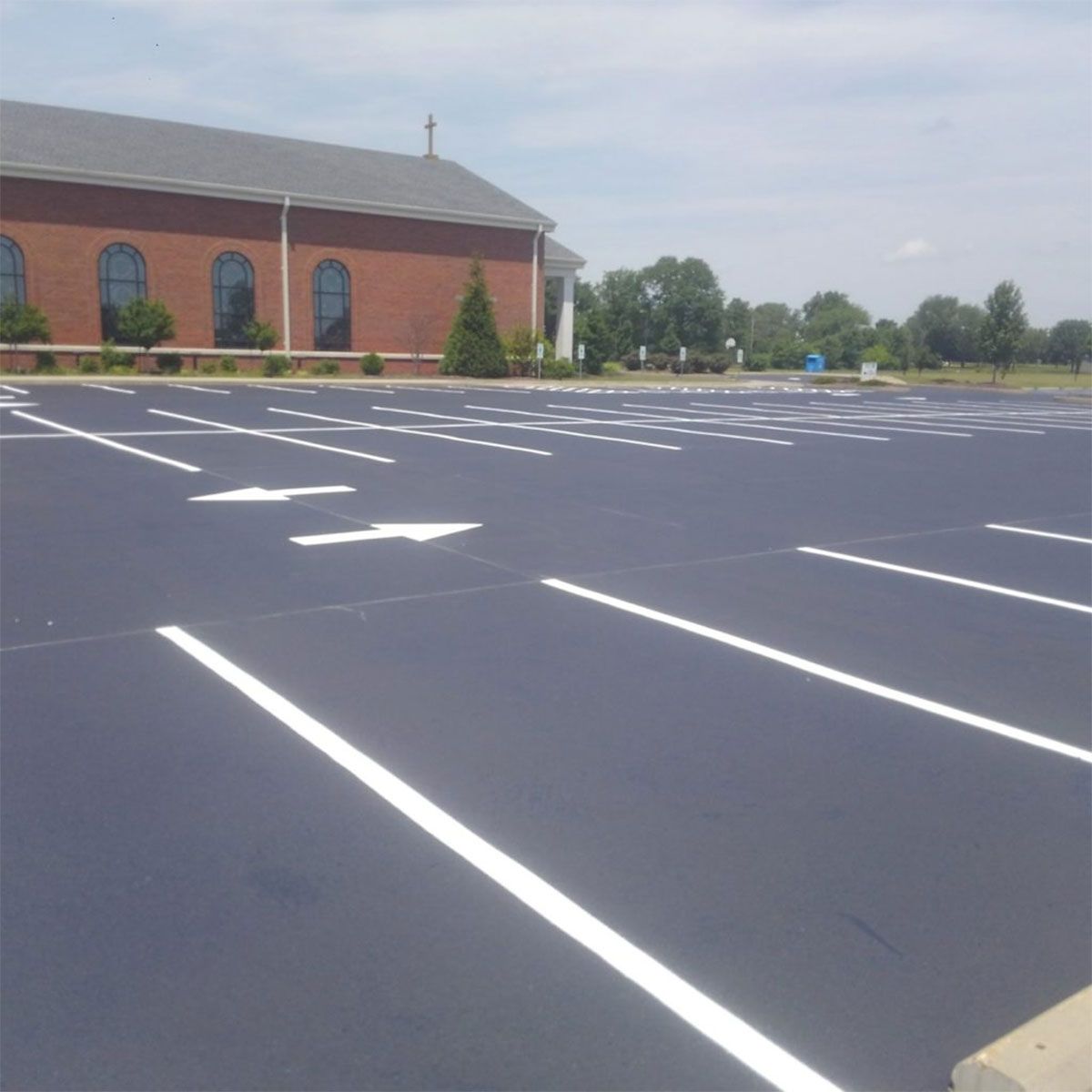 Empty parking lot with white striped spaces beside a brick building on a clear day