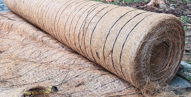 Close-up of a rolled burlap mat lying on the ground outdoors