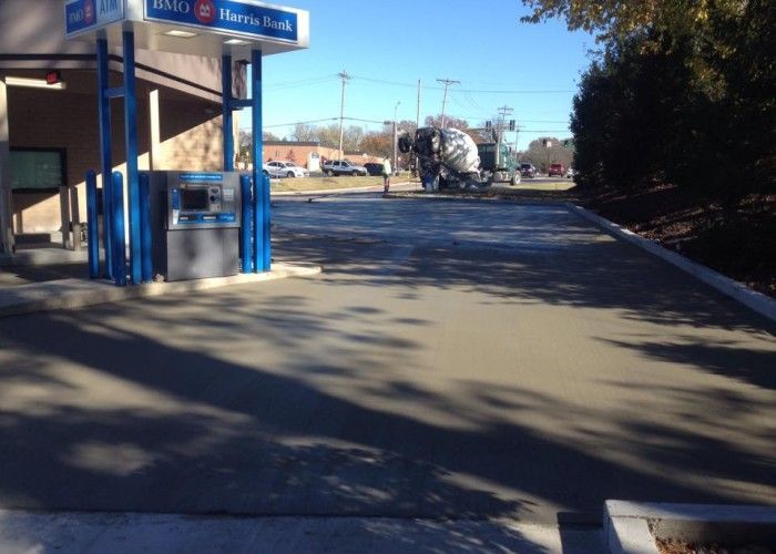Blue bus stop shelter beside a quiet road with long shadows and parked vehicles in the distance