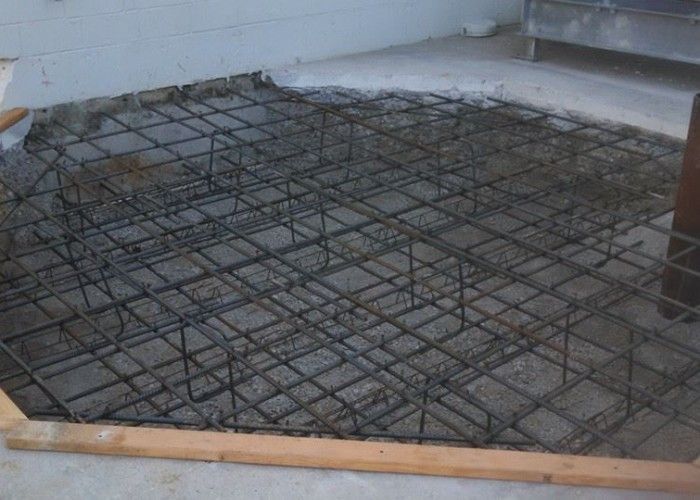 Steel rebar grid laid over a concrete slab form, ready for pouring.